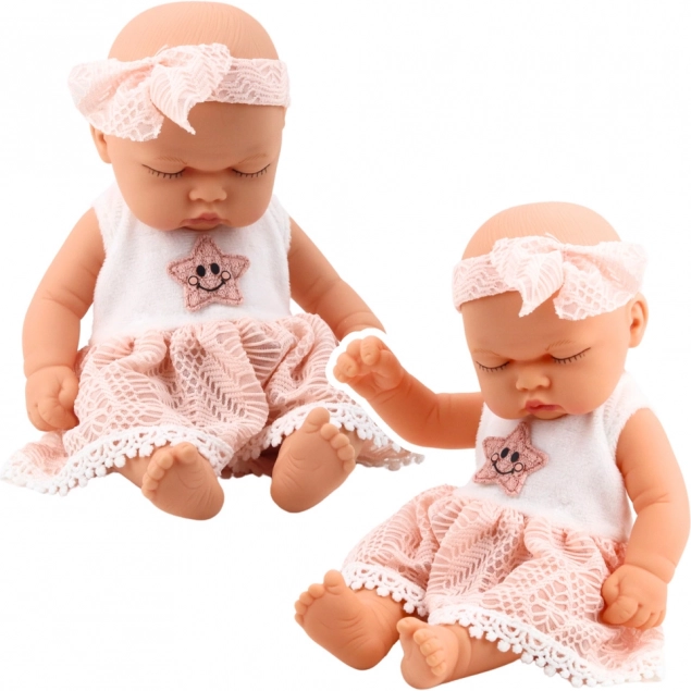 Bambola neonata che dorme in abito rosa con pizzo e fascia con stelline